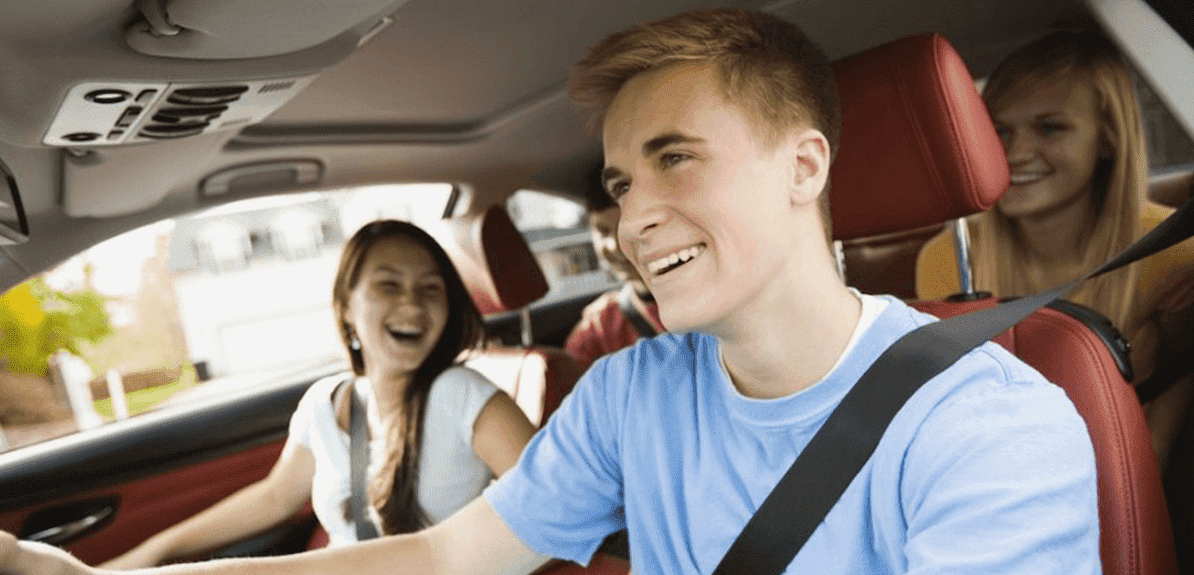 Teenaged boy driving with teenaged girl in passenger seat